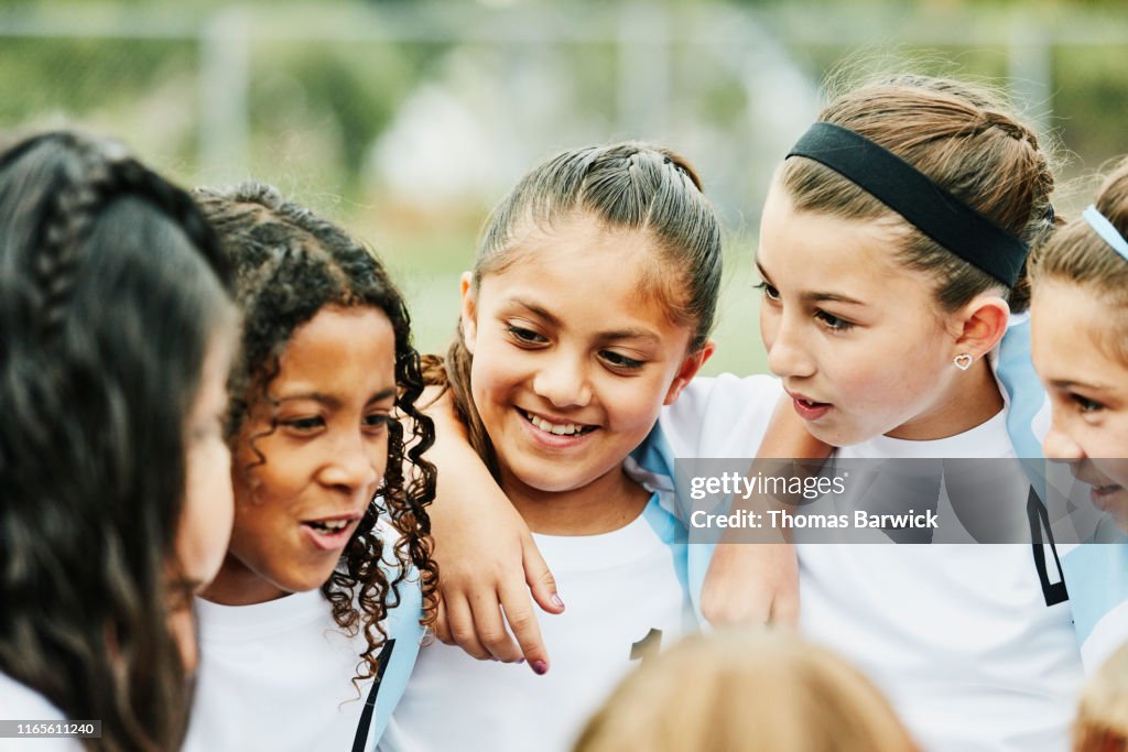 Smiling young female soccer players with arms around each other
