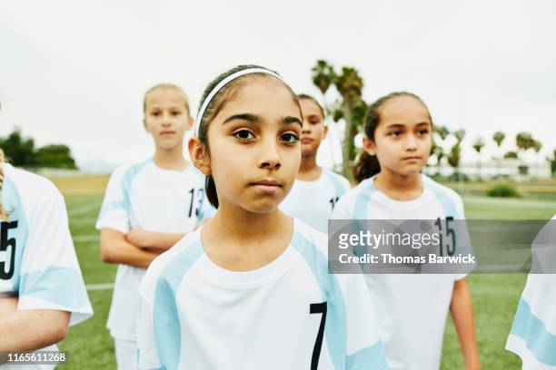 portrait of serious young female soccer player standing on field with teammates - american football field photos et images de collection