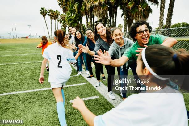 young female soccer players high fiving parents on sidelines after soccer game - fussball team stock-fotos und bilder