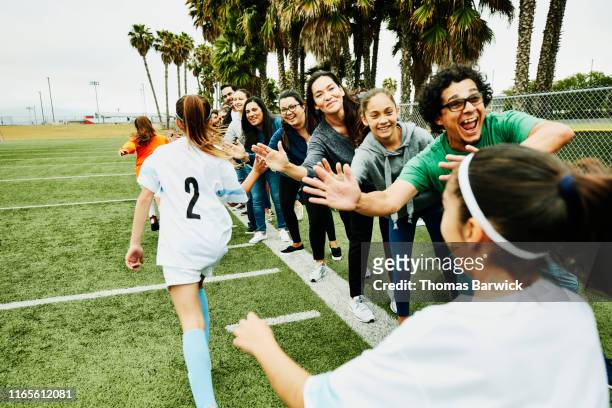young female soccer players high fiving parents on sidelines after soccer game - friendly match photos et images de collection
