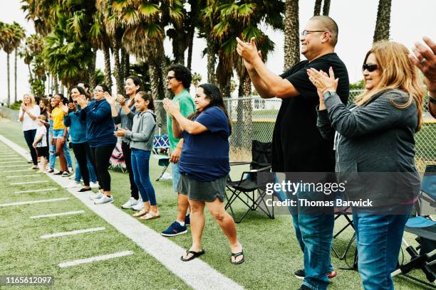 parents and families on sideline of field cheering for soccer players - fan appreciation day stock-fotos und bilder