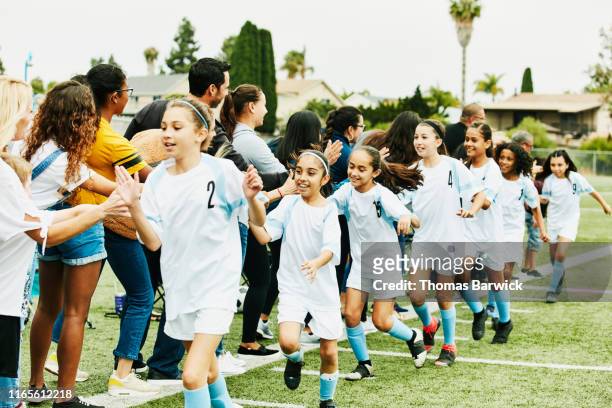 young female soccer team giving high fives to parents on sidelines after game - soccer team stock pictures, royalty-free photos & images