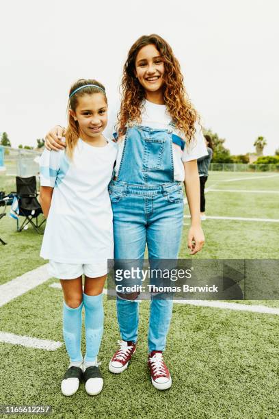 portrait of young female soccer player and sister standing on field after game - 13 year old girls in shorts stock pictures, royalty-free photos & images
