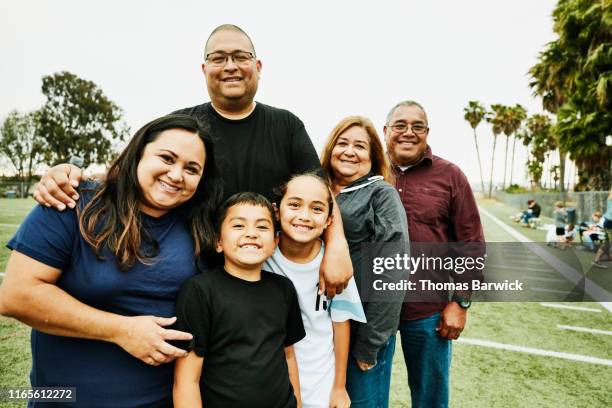 portrait of multigenerational family on field after daughters soccer game - sportveranstaltung stock-fotos und bilder