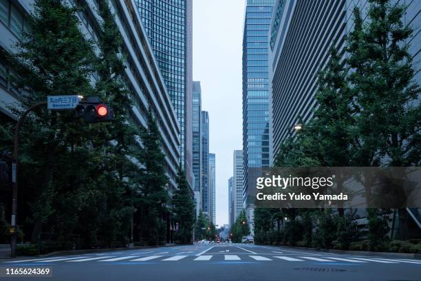 road amidst high-rise building during morning - marunouchi stock-fotos und bilder