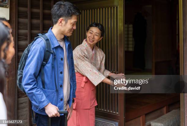 traditionally dressed japanese woman bowing to visitors to her inn - japanese greeting stock pictures, royalty-free photos & images