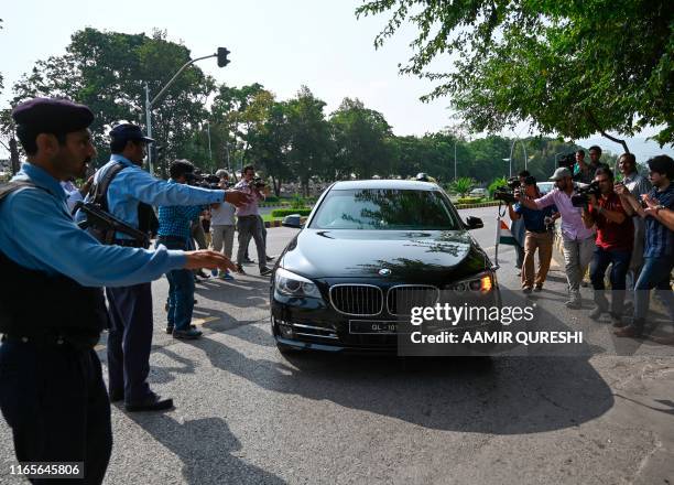 Pakistani policemen make way for a car carrying Indian diplomats as they leave the Pakistan's Foreign Ministry building after meeting with an Indian...