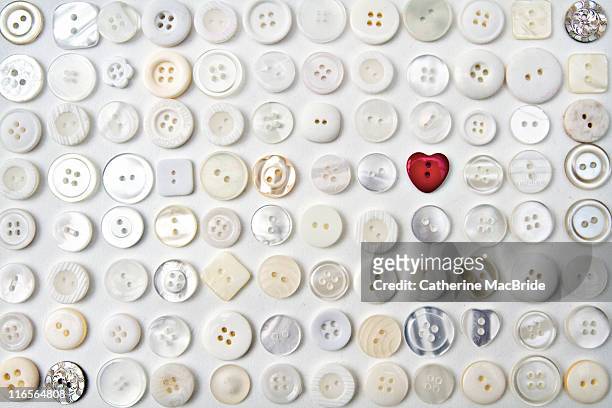 red heart button among white buttons - catherine macbride stock pictures, royalty-free photos & images
