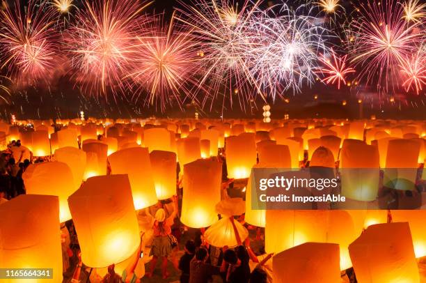 numerous paper lanterns prepared for floating in the sky with fireworks in the background - thailand illumination festival bildbanksfoton och bilder