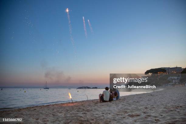 amis catalans appréciant des feux d'artifice sur la plage de roses au coucher du soleil - province-de-barcelone photos et images de collection