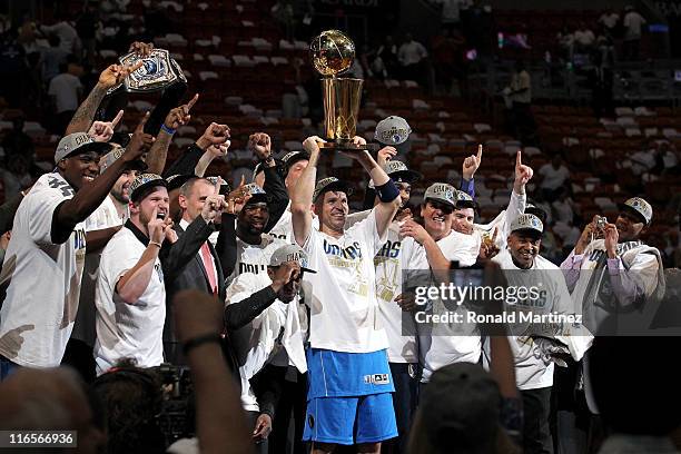 Jason Kidd of the Dallas Mavericks holds up the Larry O'Brien Championship trophy as he celebrates with his teammates and team owner Mark Cuban after...