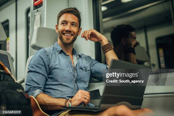 moderne man met laptop in de trein - passenger muzikant stockfoto's en -beelden