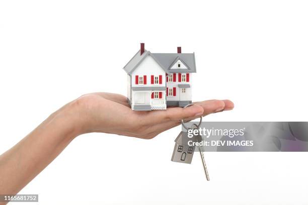 model house and key in woman's hand against white background - house key hands stock pictures, royalty-free photos & images