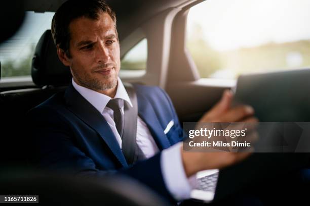 handsome businessman sitting with laptop on the backseat of the car stock photo - audi interior stock pictures, royalty-free photos & images