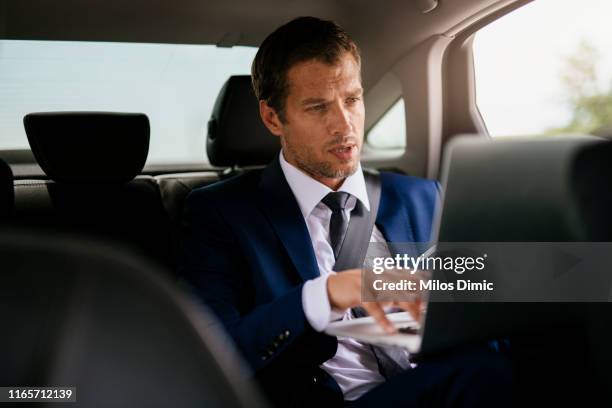 handsome businessman sitting with laptop on the backseat of the car stock photo - audi interior stock pictures, royalty-free photos & images