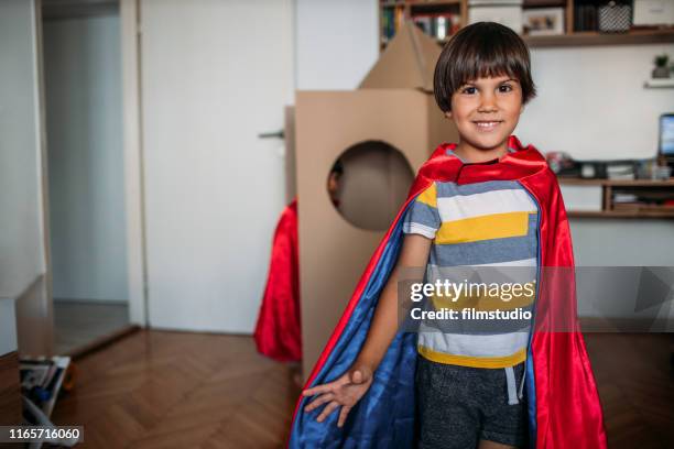adorable little boy dressed like a superhero playing with cardboard rocket at home - cardboard cut out stock pictures, royalty-free photos & images