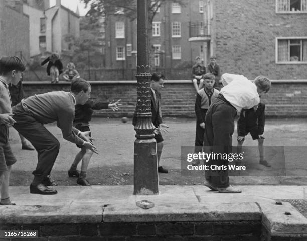British bishop and cricket player David Sheppard , curate at St Mary's Church, playing cricket, as wicket-keeper, with local boys in the street,...