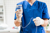 Doctor in blue uniform holding drip iv and infusion pump. Medical treatment emergency concept.. Intravenous fluid for seriously patient in the emergency room at hospital.