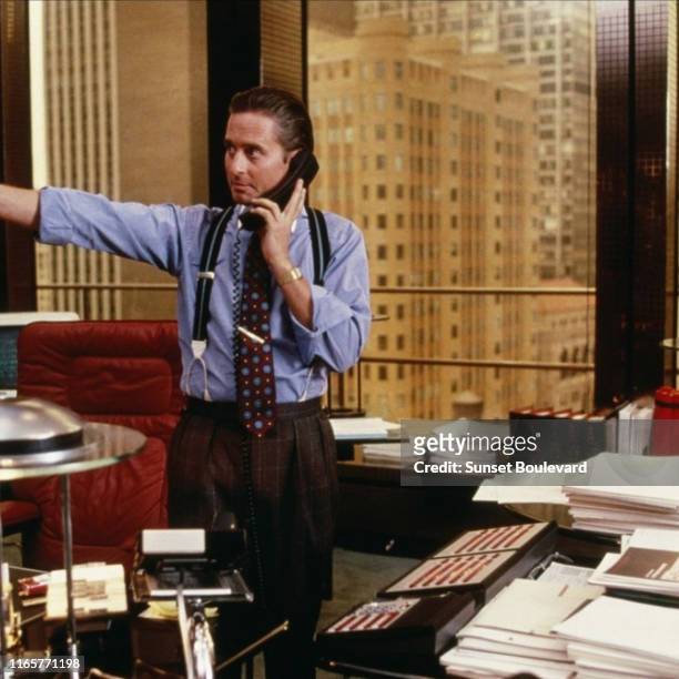 American actor Michael Douglas speaks on the telephone in a scene from the film 'Wall Street' , New York, New York, 1987. The scene was filmed in a...