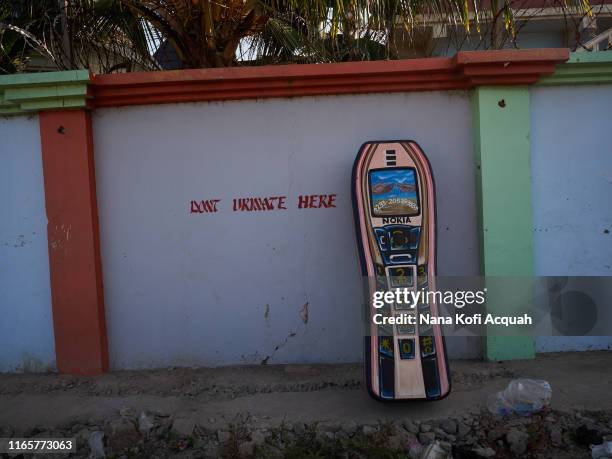 Nokia phone fantasy coffin designed by Eric Kpakpo Adotey, and painted by Joseph Adjetey Sowah perches on a wall on June 21, 2019 in La Accra, Ghana....