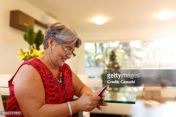 grand mother send marry christmas on smart phone - fat old lady stock pictures, royalty-free photos & images