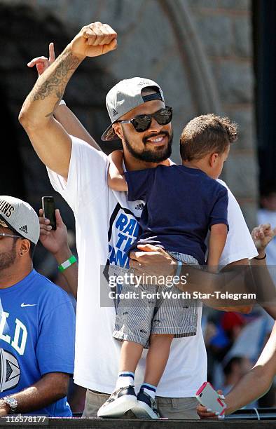 Dallas Mavericks player Tyson Chandler waves to the crowd while holding his son during the Mavericks victory parade through downtown Dallas, Texas,...