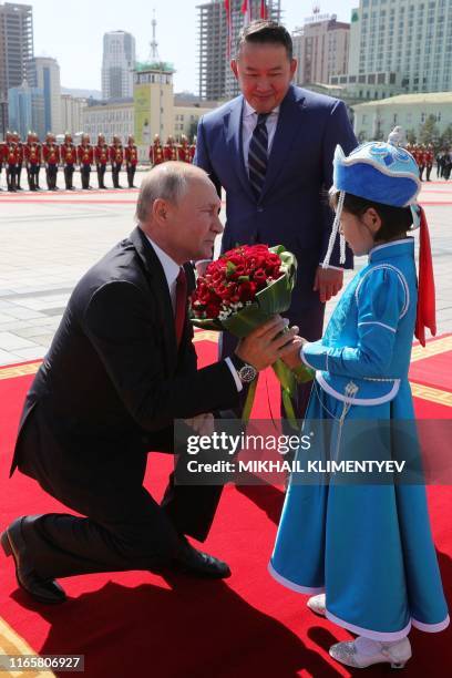 Russia's President Vladimir Putin receive a flower bouquet next to Mongolia's President Khaltmaagiin Battulga during a welcoming ceremony before...