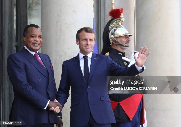 French President Emmanuel Macron waves as he welcomes Republic of the Congo's President Denis Sassou Nguesso at the Elysee Palace in Paris on...
