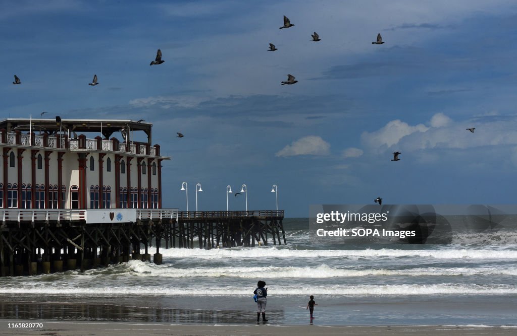 A woman and a child watch the heavy surf caused by Hurricane...