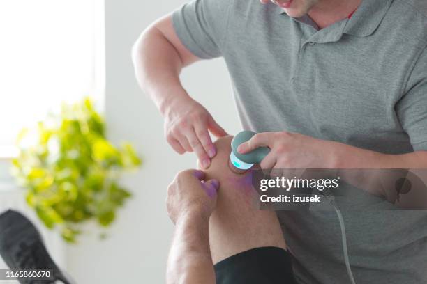 fisioterapeuta que trata al hombre con ultrasonido - laser therapy fotografías e imágenes de stock