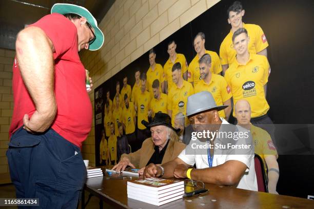 Umpire John Holder and artist Paul Trevillion at a book signing of 'You are the Umpire' during day two of the First Specsavers Test Match between...