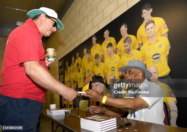 Umpire John Holder and artist Paul Trevillion at a book signing of 'You are the Umpire' during day two of the First Specsavers Test Match between...