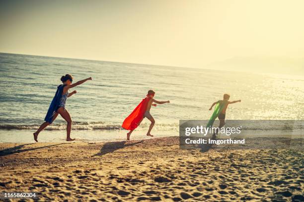 kids superhelden spelen op het strand - summer super 8 stockfoto's en -beelden