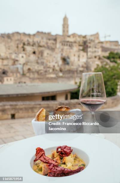 matera, typical food plate with peperoni cruschi and town in background - matera stock-fotos und bilder