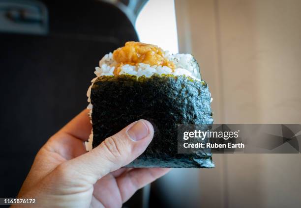 hand holding a onigiri or rice ball on a train - rice ball stock pictures, royalty-free photos & images