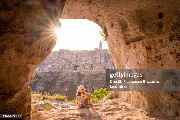 tourist woman admiring matera from a cave at sunset, basilicata, italy - bari italy stockfoto's en -beelden