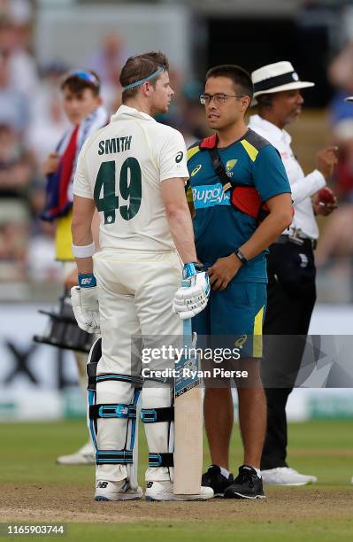 Steve Smith of Australia is assessed Australian Team Doctor Richard Saw after being struck on the helmet by a delivery from Ben Stokes of England...