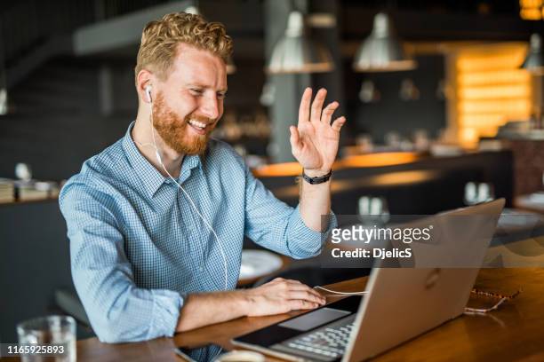 gelukkige jonge zakenman zwaaiende naar een online cliënt. - demonstration stockfoto's en -beelden