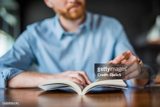 jonge man het lezen van een boek hand close-up. - lezen stockfoto's en -beelden