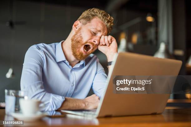 tired young man working in coffee shop and yawning. - itchy eyes stock pictures, royalty-free photos & images