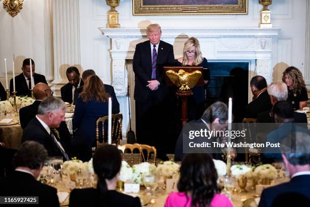 President Donald J. Trump listens as Pastor Paula White leads a prayer at a dinner celebrating Evangelical leadership in the State Dining Room of the...