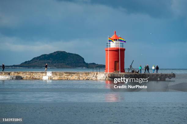 The historic and picturesque Molja Lighthouse at the entrance of the harbour, port of Alesund town, Norway, with an anchor and LGBT flags, nowadays...