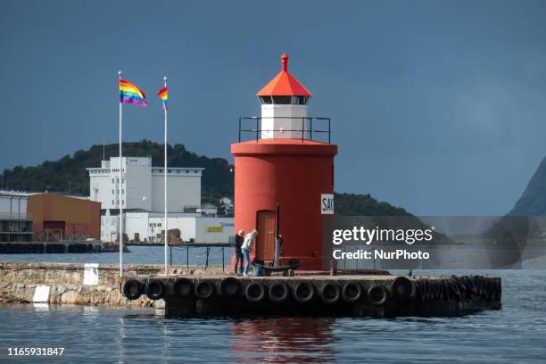 The historic and picturesque Molja Lighthouse at the entrance of the harbour, port of Alesund town, Norway, with an anchor and LGBT flags, nowadays...