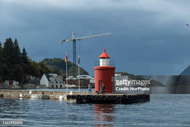 The historic and picturesque Molja Lighthouse at the entrance of the harbour, port of Alesund town, Norway, with an anchor and LGBT flags, nowadays...