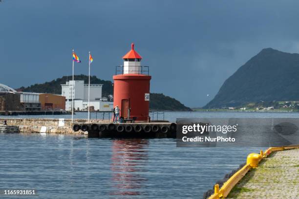 The historic and picturesque Molja Lighthouse at the entrance of the harbour, port of Alesund town, Norway, with an anchor and LGBT flags, nowadays...