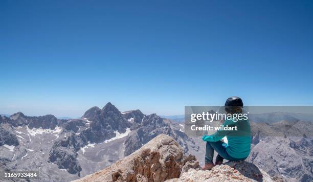 female mountain climber is looking at the map in the summit of a mountain - altitude training stock pictures, royalty-free photos & images