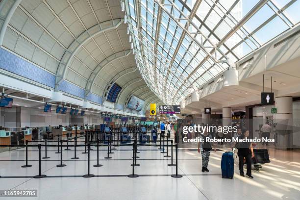 Pearson International Airport terminal 3 during the morning hours. The sunlight enters through the skylights in the ceiling. Passengers walk in the...