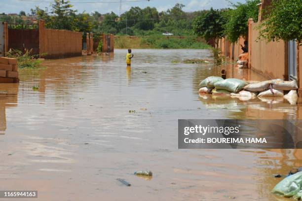 Child wades through water on a flooded street in the Kirkissoye quarter in Niamey on September 3, 2019. - Several quarters of the Nigerian capital...