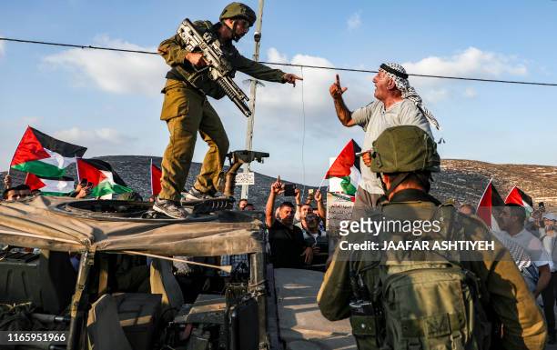 Palestinian protester yells at an Israeli soldier as he confronts him atop an Israeli army vehicle during a protest against Israeli forces conducting...