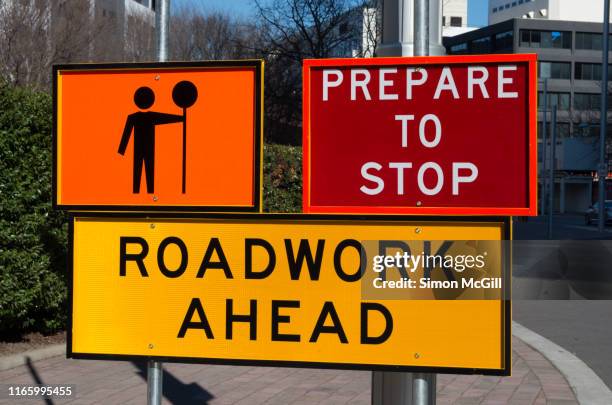 signs warning drivers to prepare to stop and heed the worker with a stop sign because of roadwork ahead - road construction flagger stock pictures, royalty-free photos & images